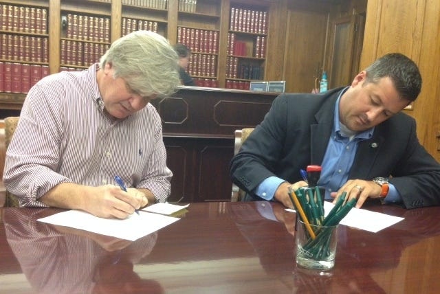 John Lyon • Arkansas News Bureau / David Couch, left, chairman of Let Arkansas Decide, and Rob Hammons, director of elections for the secretary of state's office, sign paperwork Friday, Aug. 15, 2014, in Little Rock after Couch submitted 41,492 additional signatures in support of a proposed constitutional amendment to allow statewide alcohol sales.