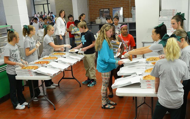 BRIAN D. SANDERFORD TIMES RECORD / Chaffin Junior High School cheerleaders serve pizza to students entering the seventh grade on Thursday, Aug. 14, 2014. The students were participating in the Fort Smith Public Schools' "Transition to Success" program. Each junior high gives the incoming seventh grade class a chance to experience a day in their new school, without the upper grades, prior to the first day of school. Students learned about clubs and organizations they can join, meet teachers, received IDs, lockers, and learned procedures for classroom and cafeteria.