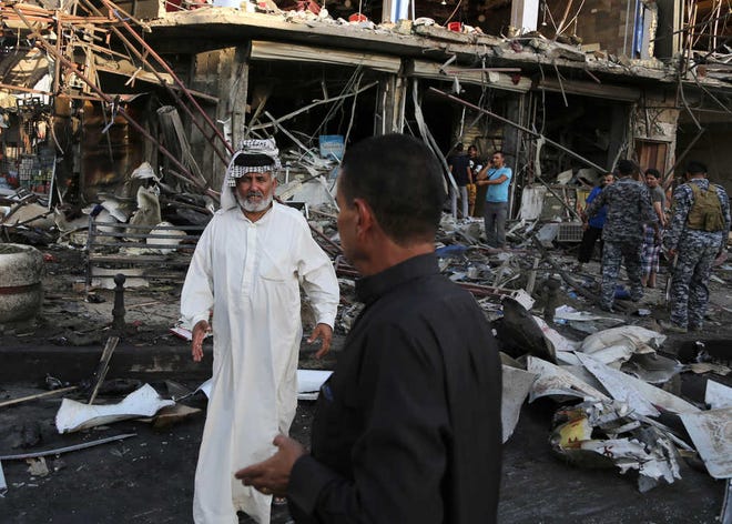 Iraqi policemen and civilians inspect the site of a car bomb attack near a restaurant in Baghdad, Iraq.