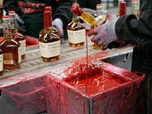 FILE - In this Wednesday, April 8, 2009, file photo, a bottle of Maker's Mark bourbon is dipped in red wax during a tour of the distillery in Loretto, Ky. Kentucky bourbon makers have stashed away their largest stockpiles in more than a generation due to resurgent demand for the venerable brown spirit. (AP Photo/Ed Reinke, File)
