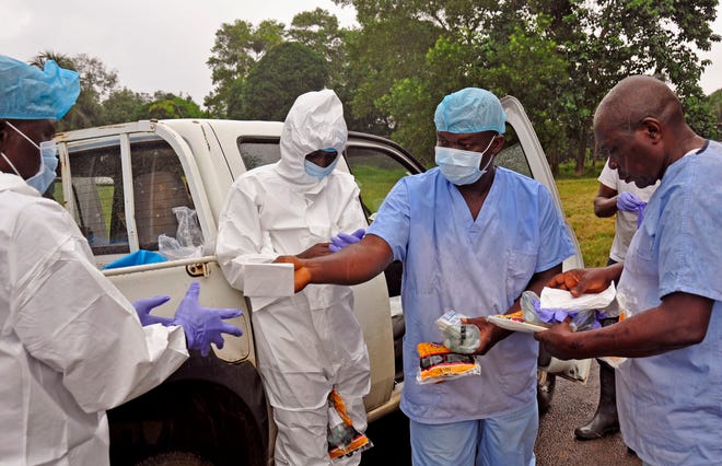Health workers are handed personal protective gear by a team leader, right, before collecting the bodies of the deceased from streets in Monrovia, Liberia, Saturday, Aug. 16, 2014. New figures released by the World Health Organization showed that Liberia has recorded more Ebola deaths — 413 — than any of the other affected countries. (AP Photo/Abbas Dulleh)