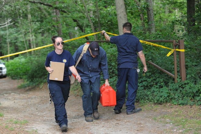 State medical examiner officials walk back from a site in Beebe Woods Conservation area in Falmouth where human remains were found off a walking trail. Falmouth police at the scene say the conservation area is closed to users.