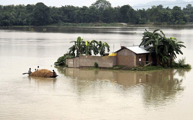 Indian villagers move in a country boat through a flooded village in Morigaon district of northeastern Assam state, India.
