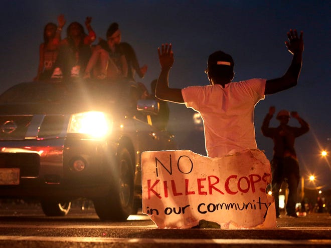 People protest Sunday for Michael Brown, who was killed by a police officer last Saturday in Ferguson, Mo. As night fell Sunday in Ferguson, another peaceful protest quickly deteriorated after marchers pushed toward one end of a street. Police attempted to push them back by firing tear gas and shouting over a bullhorn that the protest was no longer peaceful.