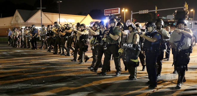 Police advance to clear people Monday, Aug. 18, 2014, during a protest for Michael Brown, who was killed by a police officer Aug. 9 in Ferguson, Mo. Brown’s shooting has sparked more than a week of protests, riots and looting in the St. Louis suburb.