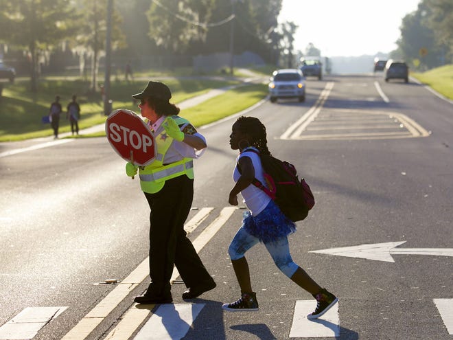 Crossing guard Filomena Walsh helps a student get to class in the crosswalk at Greenway Elementary on Midway Road in Ocala on Tuesday.