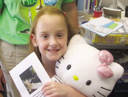 Kiki Evans photo
Morgan Magliaro happily embraces “Kitty” and the photo album documenting Kitty’s activities while at the Stuffed Animal Sleepover at Seabrook Library Tuesday night.