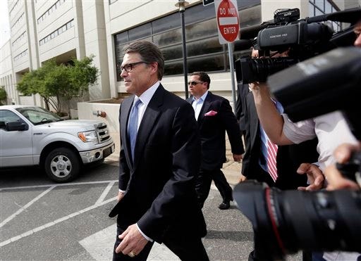 Texas Gov. Rick Perry, left, leaves the Blackwell Thurman Criminal Justice Center after he was booked, Tuesday, Aug. 19, 2014, in Austin, Texas. Perry was indicted last week on charges of coercion and official oppression for publicly promising to veto $7.5 million for the state public integrity unit run. (AP Photo/Eric Gay)