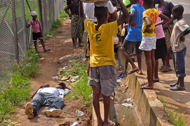 Children surround a man, left, that fell down while walking on a street suspected of having contracted the Ebola virus in the city of Monrovia, Liberia, Tuesday, Aug. 19, 2014. The World Health Organization says the outbreak has killed more than 1,200 people, while authorities struggle to contain its spread and treat the sick. (AP Photo/Abbas Dulleh)