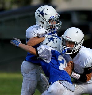Grant Saucer, middle, tries to get around the block of Blake Woods, right, to make a tackle on Chase Oliver during MCYFL Junior Cowboys practice Monday night. The league's 44th season opens with a jamboree Saturday at Jervey Gantt Park.