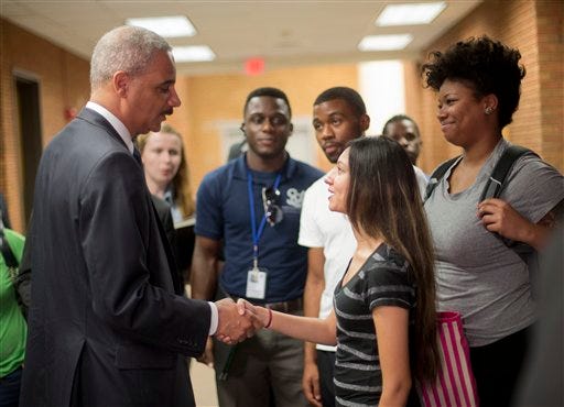 Attorney General Eric Holder shakes hands with Bri Ehsan, 25, right, following his meeting with students at St. Louis Community College Florissant Valley in Ferguson, Mo., Wednesday, Aug. 20, 2014. Holder arrived in Missouri on Wednesday, a small group of protesters gathered outside the building where a grand jury could begin hearing evidence to determine whether a Ferguson police officer who shot 18-year-old Michael Brown should be charged in his death. (AP Photo/Pablo Martinez Monsivais/Pool)