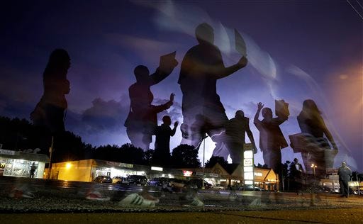 In this photo taken with a long exposure, protesters march in the street as lightning flashes in the distance in Ferguson, Mo., on Wednesday, Aug. 20, 2014. On Aug. 9, a white police officer fatally shot unarmed Michael Brown, a black 18-year-old, in the St. Louis suburb.