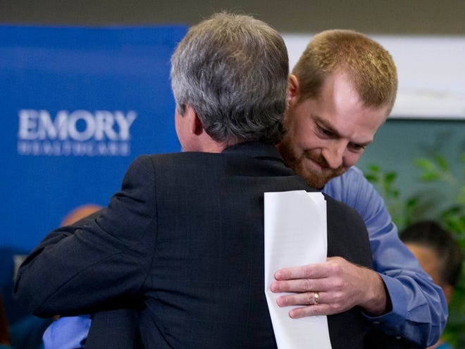 Ebola victim Dr. Kent Brantly, right, hugs a member of the medical staff that treated him, after being released from Emory University Hospital Thursday in Atlanta.