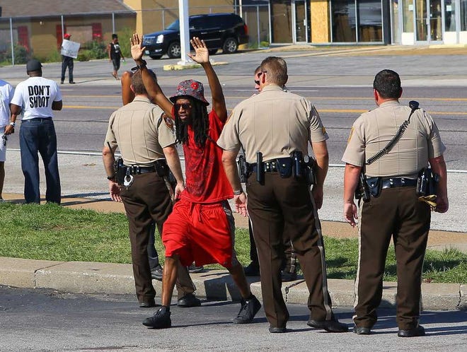 Jarvis Hollis of St. Louis puts his hands up saying, "don't shoot" as he goes out of his way to walk between St. Louis County Police on West Florissant Avenue on Tuesday, Aug. 19, 2014, in Ferguson, Mo. (Curtis Compton/Atlanta Journal-Constitution/MCT)