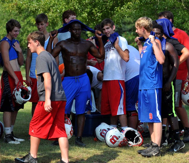 Berry High School football players retreat to shade and use cooling towels to help manage the heat of summer football drills.       Photo | Tommy Williams