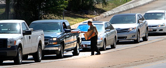 A panhandling gets money from a motorist at street corner of NE 23 and Santa Fe, Friday, August 22, 2014. Photo by David McDaniel