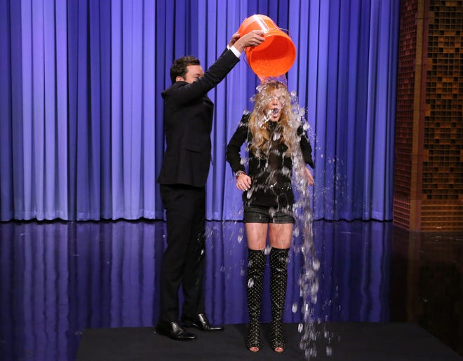 This Aug. 20, 2014 photo released by NBC shows host Jimmy Fallon, left, dumping a bucket of ice water over the head of actress Lindsay Lohan as she participates in the ALS Ice Bucket Challenge on "The Tonight Show Starring Jimmy Fallon," in New York.