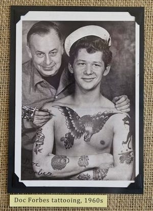 a 1960s photograph of tattoo artist Doc Forbes with a young client is displayed at the Tattoo Archive in downtown Winston-Salem, N.C. (AP Photo/Winston-Salem Journal, David Rolfe)