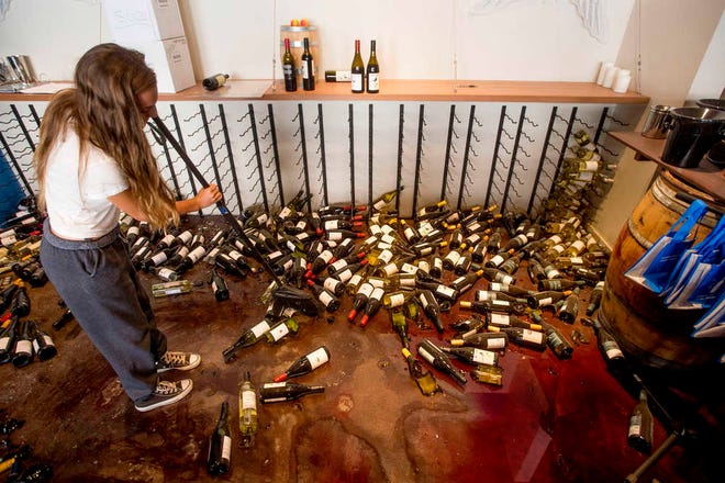 Grace Hardy cleans up wine bottles at nakedwines.com in Napa, Calif., following an earthquake Sunday, Aug. 24, 2014. Winemakers in California's storied Napa Valley woke up to thousands of broken bottles, barrels and gallons of ruined wine as a result of Sunday's earthquake. (AP Photo/Noah Berger)