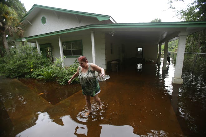 Barbara LeCompt wades through floodwater at the Deer Point-area home of her client, homeowner Grover Stamps Jr., in August 2013, when Bay County saw its second major flood event that summer. The water rose 14 inches inside the home, according to insurance adjusters.