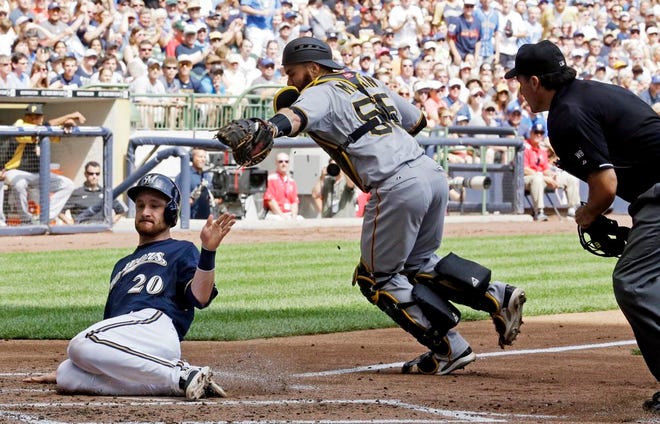 Milwaukee Brewers' Jonathan Lucroy (20) slides safely past Pittsburgh Pirates catcher Russell Martin, center, during the second inning of a baseball game Sunday, Aug. 24, 2014, in Milwaukee. Lucroy scored from second on a hit by Aramis Ramirez.