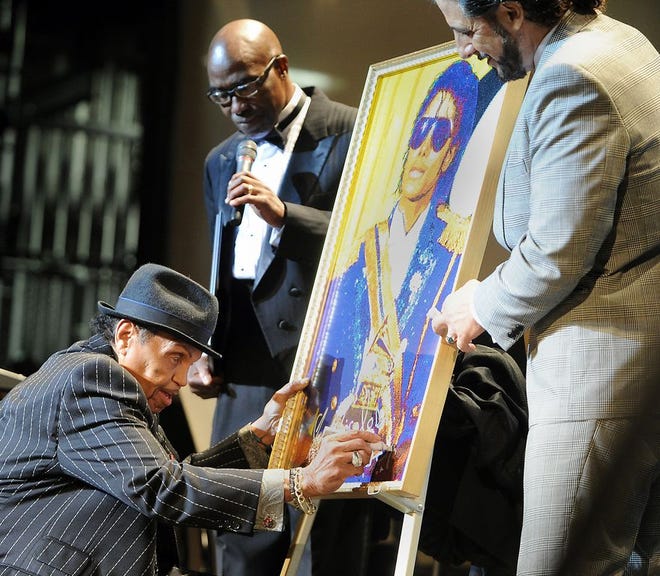 Joe Jackson (above left) signs a painting of his son, Michael Jackson. The artwork will become part of the collection for the official R&B Music Hall of Fame Museum.