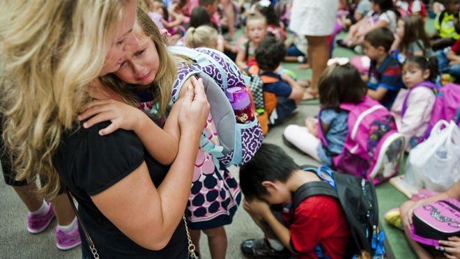 Lauren Adkins, left, comforts her daughter, Kenna Adkins, 5, during first day of school activities at Reed Elementary in Cedar Park.