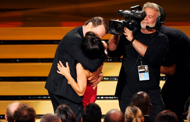 Bryan Cranston kisses Julia Louis-Dreyfus, center front, as she accepts the award for outstanding lead actress in a comedy series for her work on “Veep” at the 66th Annual Primetime Emmy Awards at the Nokia Theatre L.A. Live on Monday, Aug. 25, 2014, in Los Angeles.