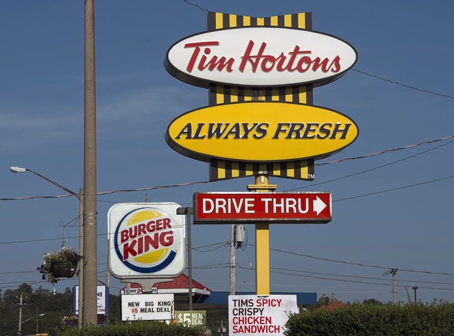 A Burger King sign and a Tim Hortons sign are displayed in Lower Sackville, Nova Scotia, Monday, Aug. 25, 2014. Burger King is in talks to buy Tim Hortons in hopes of creating a new, publicly traded company with its headquarters in Canada.