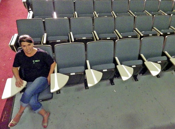 Angelina Doyle, executive director at New Bern Civic Theatre, sits in one of the 200 newly donated seats from Craven Community College.