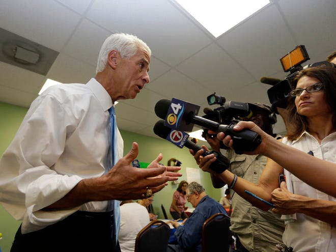 Former Florida Gov. Charlie Crist , left, answers questions by the news media during a visit to a phone bank, Monday, Aug. 25, 2014, in Fort Lauderdale, Fla. Crist is running against opponent Nan Rich for the democratic nomination for Florida Governor. Florida's primary election is Tuesday.