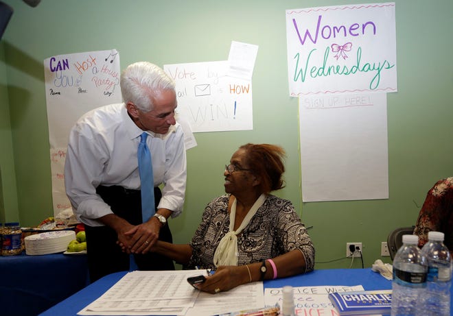 Former Florida Gov. Charlie Crist, left, talks with volunteer Gloria Huntley, of Lauderhill, Fla., right, during a visit to a phone bank, Monday, Aug. 25, 2014, in Fort Lauderdale, Fla.