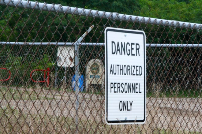 Signs warning of hazardous waste hang on the fence surrounding the former Ionia City Landfill on Cleveland Street. The Fred Thwaites Grand River Trail runs between the two sections of the site, which is one of 1,700 EPA-designated Superfund sites.