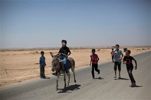A Syrian refugee boy, followed by other children, enjoys riding a rented donkey pulled by his owner, during the Eid al-Fitr holiday that marks the end of the holy fasting month of Ramadan, at Zaatari refugee camp, near the Syrian border, in Mafraq, Jordan, Wednesday, July 30, 2014. More than 2.8 million Syrian children inside and outside the country — nearly half the school-aged population — cannot get an education because of the devastation from the civil war, according to the U.N. children's agency, UNICEF.