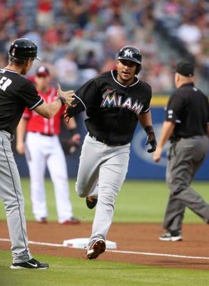 Miami's Donovan Solano is congratulated by Marlins third base coach Brett Butler after Solano's solo home run off Braves starting pitcher Aaron Harang in the first inning.