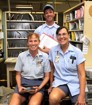 Columbia letter carriers, from left, Diane O'Meara, Larry Warren and Ann Leonard pose for a photo after receiving awards at the Columbia post office on Wednesday.
