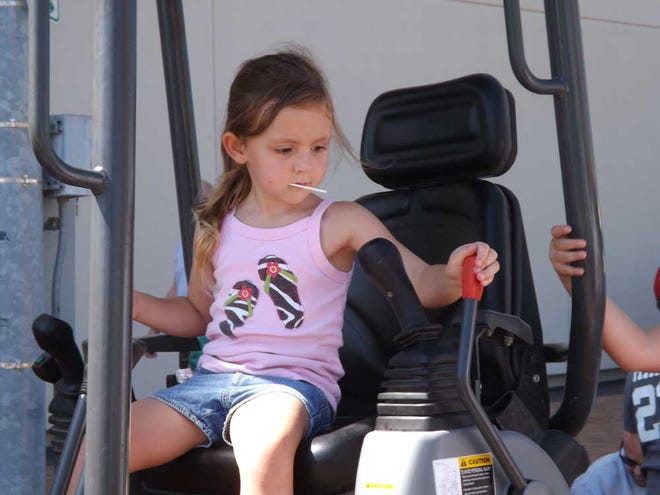 Gabby Falk, 4, explores the levers on a small backhow on Saturday morning at the Touch a Truck event near downtown. Her dad, Bryan Falk, said his two daughters weren't sure if they would like the trucks, but ended up enjoying themselves.
