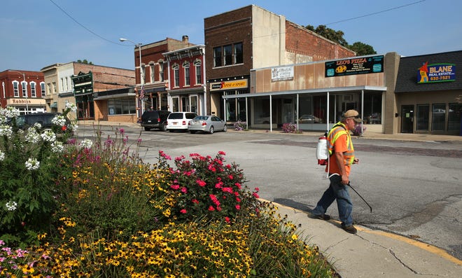 Volunteer Rick Snyder, chairman of the tree committee in Petersburg, sprays for weeds Thursday on the north side of the square. Two new businesses recently popped up along Douglas Street as Petersburg Spine & Sport, center, and Blane Real Estate, far right, relocated from elsewhere in town. Photos by David Spencer/The State Journal-Register