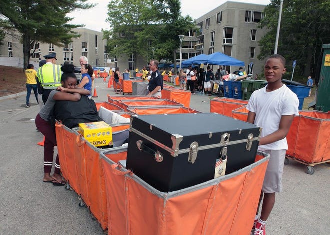Bostonians Lori Crawelle, left, and Lamare Murrell guard carts with freshman Jaliel Spencer's belongings before moving into Chestnut Hall at the University of Massachusetts Dartmouth on Sunday afternoon.