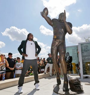 Washington Redskins quarterback Robert Griffin III looks at a bronze statute 
of himself after it was unveiled outside the new McLane Stadium before 
Sunday night's Baylor-SMU game in Waco, Texas. Griffin won the Heisman 
Trophy when he played at Baylor. ASSOCIATED PRESS / LM OTERO