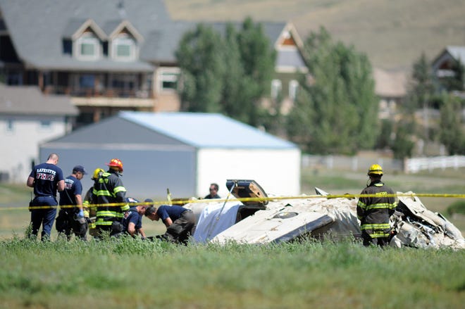 Police and firefighters work on the scene where three people were killed and two others injured after an airplane crashed in a field northwest of the main runway at Erie Municipal Airport while coming in for a landing in Erie, Colo., Sunday, Aug. 31, 2014. (AP Photo/The Daily Camera, Cliff Grassmick)