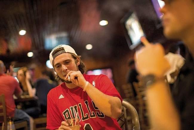 Jacob Roffol, 22, of Peoria enjoys a cigarette in the beer garden of Kouri's Pub last month. Ting Shen/Peoria Journal Star