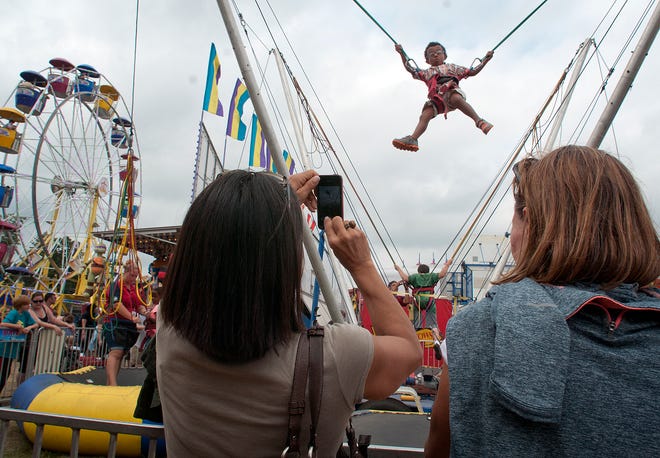 Trish Torizzo takes a picture of her 4-year-old son Henok Torizzo as he jumps on a trampoline on the Woodstock Fair midway. (T&G Staff/RICK CINCLAIR)