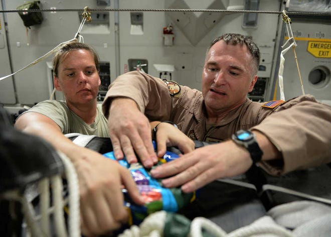 In this photo provided by the U.S. Air Force, Master Sgts. Stephen Brown, right, and Emily Edmunds, of the 816th Expeditionary Airlift Squadron loadmasters, attach candy to container delivery system bundles filled with fresh drinking water on a C-17 Globemaster III in preparation for a humanitarian airdrop over the area if Amirli, Iraq, Saturday, Aug. 30, 2014. The candy was collected by the squadron to supplement United States government humanitarian aid. (AP Photo/U.S. Air Force, Staff Sgt. Shawn Nickel)