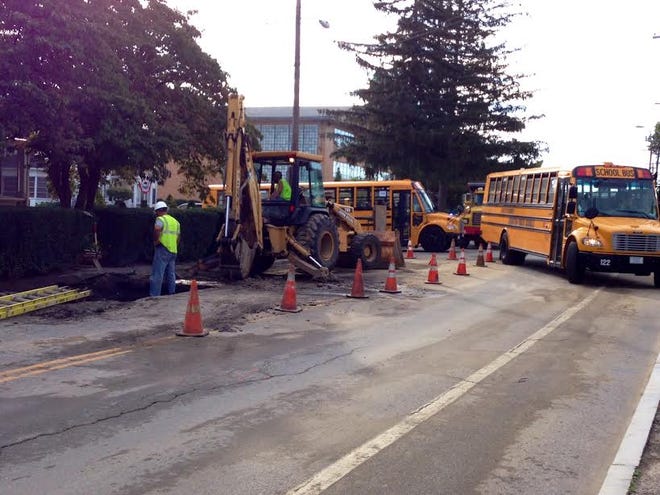 Workers repair a water main break as buses pull out of St. Rocco School onto Atwood Avenue Wednesday morning. The section of road is reduced to one lane, and police officers are directing traffic.