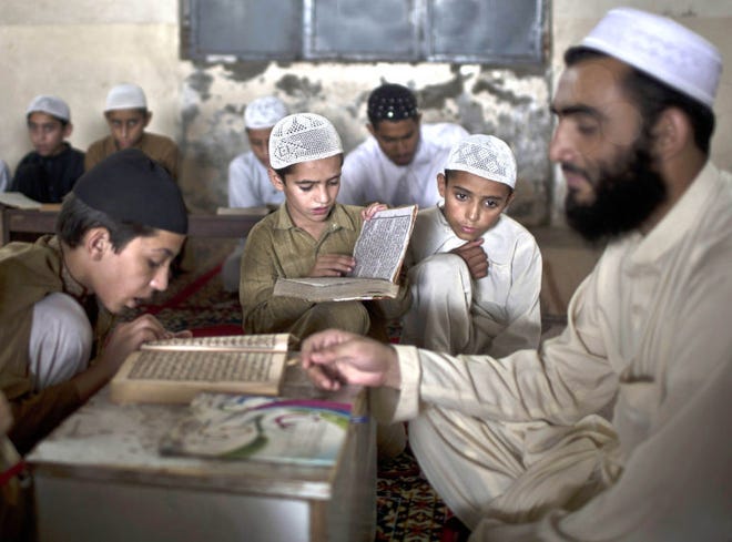 Pakistani students of a madrassa, or Islamic school, gather around their teacher during a test in reciting verses of the Quran in a mosque in Islamabad, Pakistan. Islamic schools form an important function within the Pakistani educational system, providing for many Pakistanis, the only educational institution they attend. (AP Photo/Muhammed Muheisen)