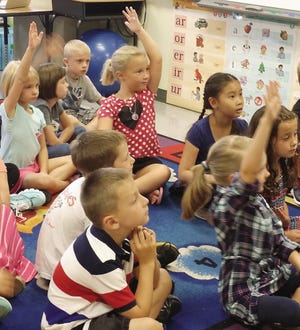 Students in Katie Jenson's second grade class at the Mildred L. Day School raise their hands to answer her question on the first day of school.