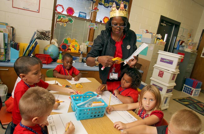 Boiling Springs Elementary School teacher assistant Juanita Surratt helps kindergarten students write sentences. She wears a crown for "Queen for a Day." Surratt was named the 2014-15 Teacher Assistant of the Year for Cleveland County Schools.