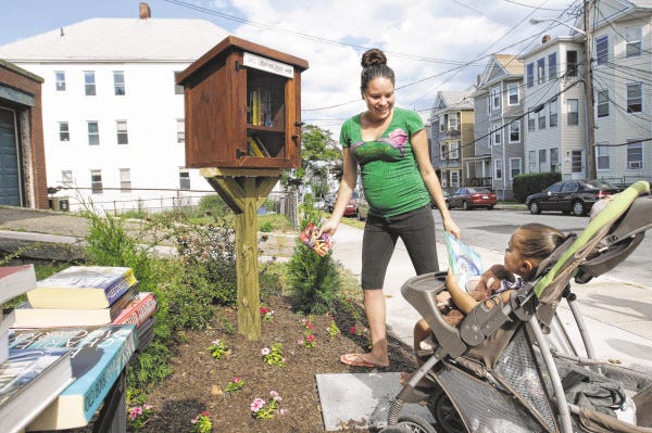 Yashaira Vargas grabs a book for herself and one for her 3-year-old daughter, Shari-Ellis Olavarria, from the Little Free Library.