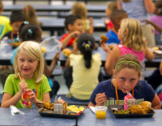 R.L. Ward Highlands Elementary School students Iana Whipple, 7, left and Bailey Blackburn, 7, right, eat their lunch Thursday morning, Sept. 4, 2014, before heading back to their classes to finish out the day. The school serves about 650 lunches a day and about 340 breakfasts each morning. Marion elementary schools began their second year of free meals for all.